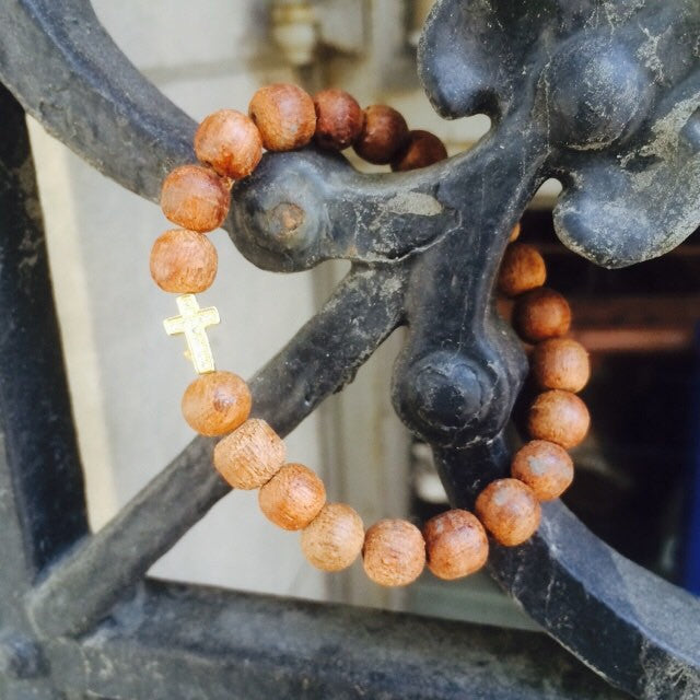 Golden cross charm is the center of attention among sandalwood beads.